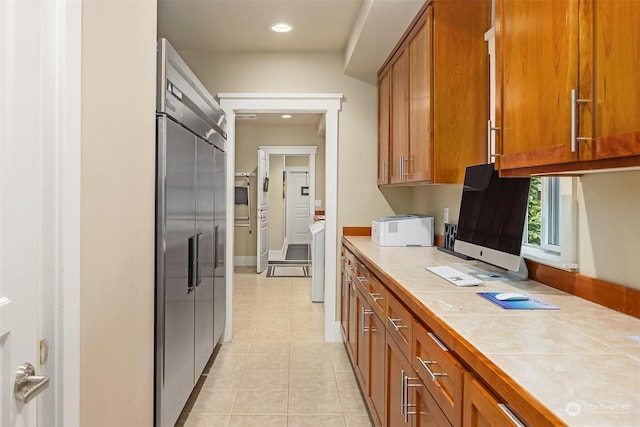 kitchen with tile counters, light tile patterned floors, and built in fridge