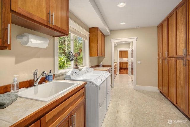 washroom featuring light tile patterned floors, sink, separate washer and dryer, and cabinets