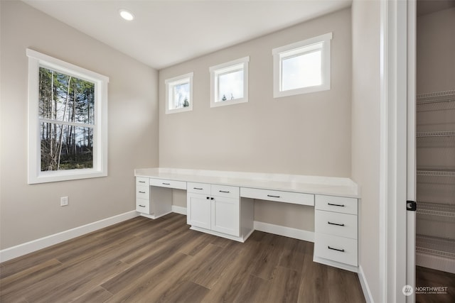 unfurnished office featuring dark hardwood / wood-style flooring and built in desk