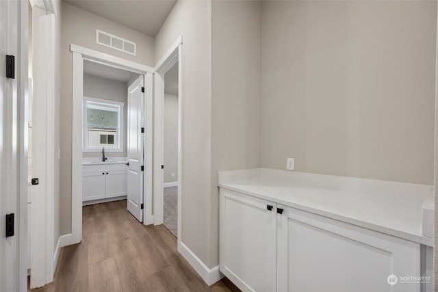 hall with light hardwood / wood-style flooring and sink