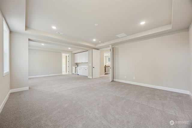 carpeted empty room featuring a tray ceiling