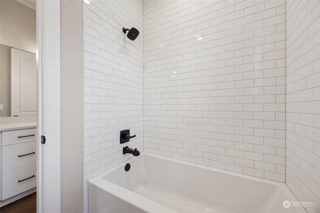 bathroom with hardwood / wood-style flooring, vanity, and tiled shower / bath