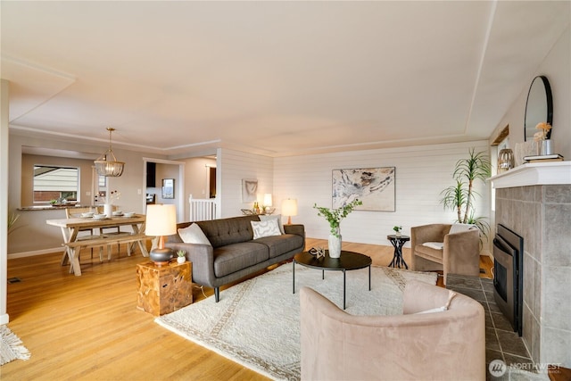 living room featuring wood finished floors, baseboards, a chandelier, and a tile fireplace