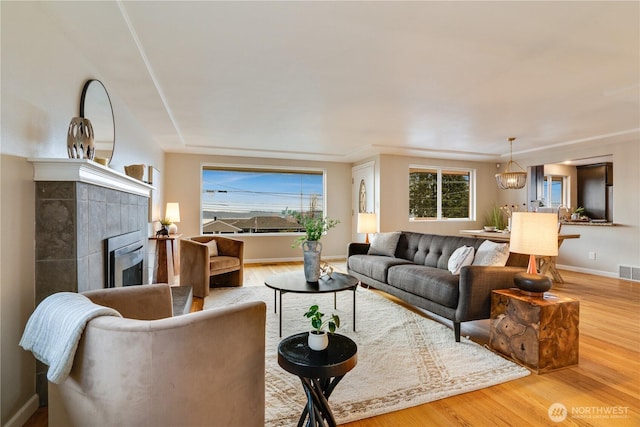 living area featuring a tiled fireplace, wood finished floors, and visible vents