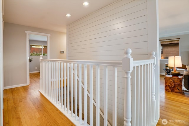 hallway featuring an upstairs landing, light wood-type flooring, and baseboards