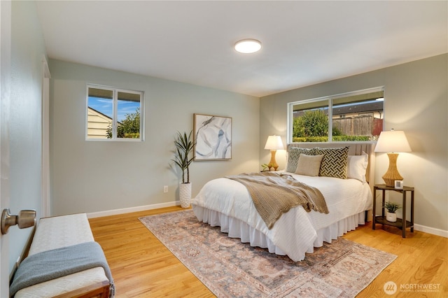 bedroom with baseboards, multiple windows, and wood finished floors