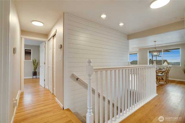 hallway with baseboards, an upstairs landing, recessed lighting, an inviting chandelier, and wood finished floors