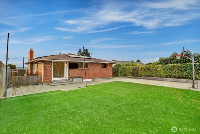 back of property with entry steps, a patio, a lawn, and brick siding