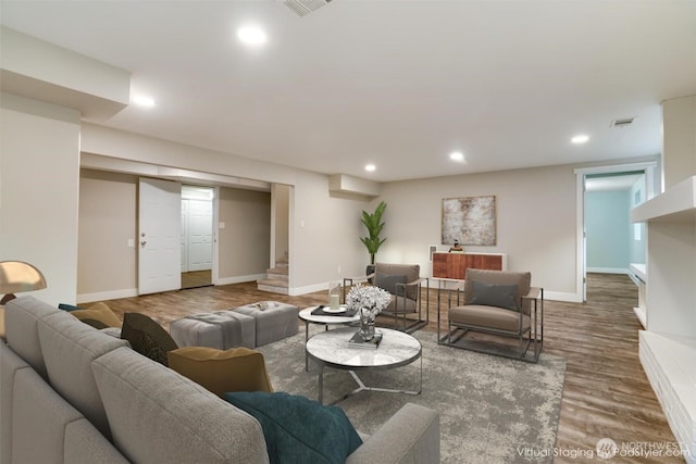 living room featuring wood finished floors, visible vents, baseboards, recessed lighting, and stairs