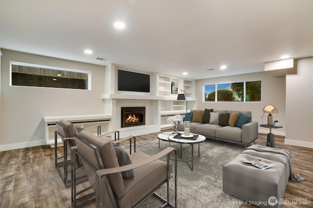 living area featuring visible vents, wood finished floors, recessed lighting, a lit fireplace, and baseboards