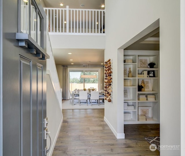 foyer featuring ornamental molding, wood-type flooring, and a high ceiling