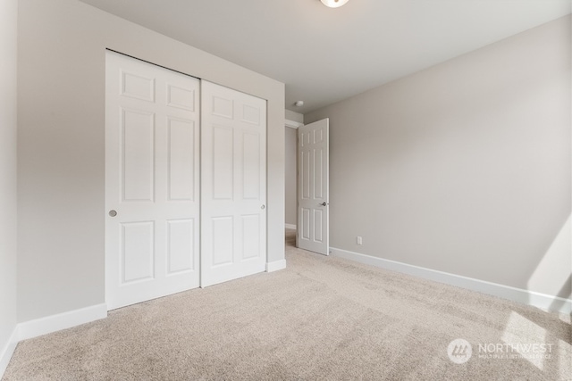 unfurnished bedroom featuring light carpet and a closet