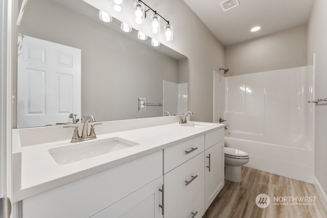 full bathroom with hardwood / wood-style flooring, toilet, vanity, and bathing tub / shower combination