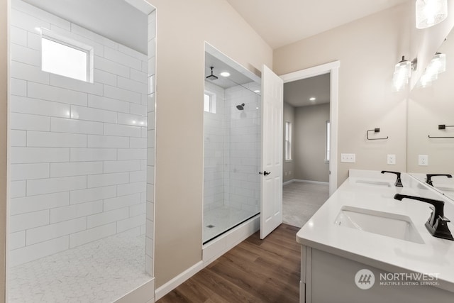 bathroom with hardwood / wood-style flooring, vanity, and a tile shower