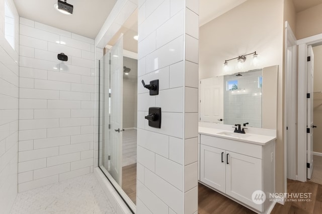 bathroom with tiled shower, vanity, and wood-type flooring