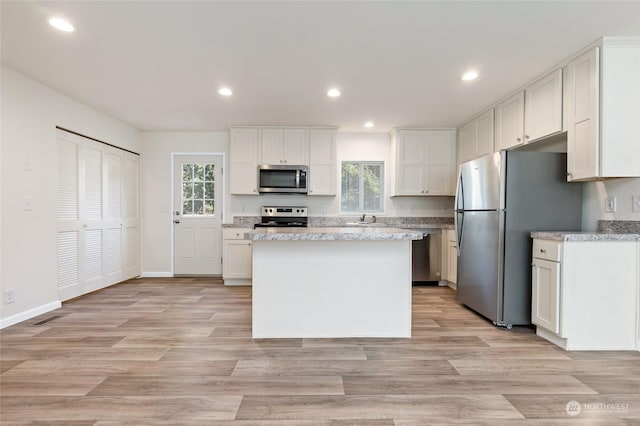 kitchen with sink, white cabinetry, a center island, appliances with stainless steel finishes, and a wealth of natural light