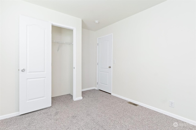 unfurnished bedroom with light colored carpet and a closet