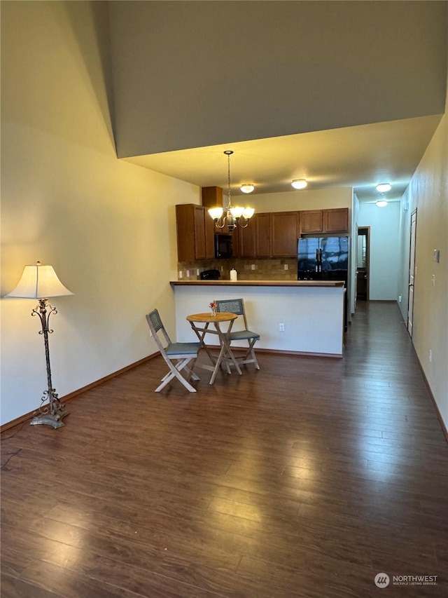 kitchen featuring pendant lighting, black appliances, decorative backsplash, kitchen peninsula, and a notable chandelier