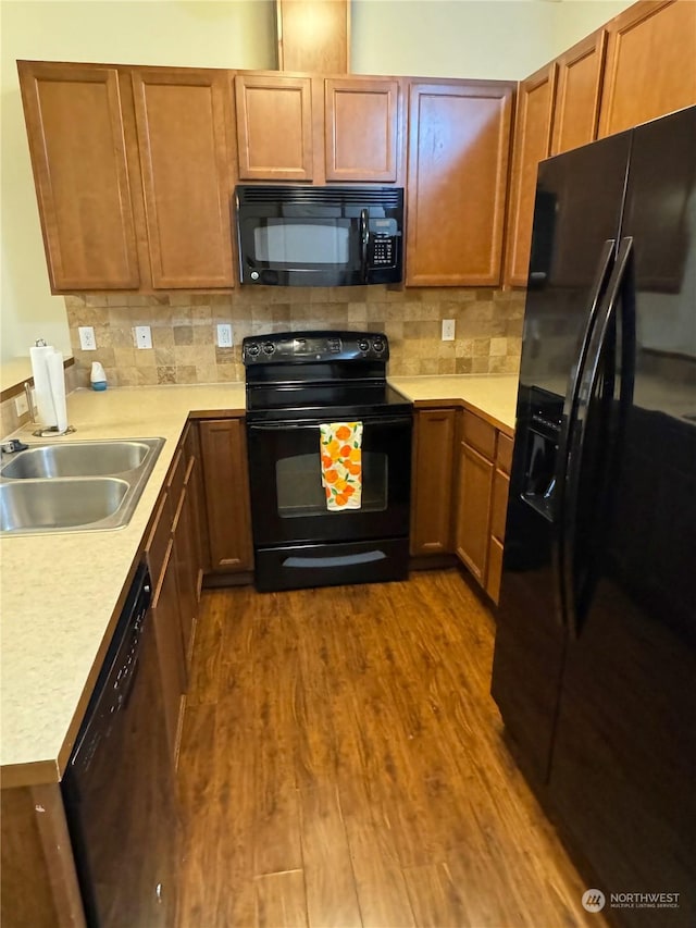 kitchen with black appliances, sink, tasteful backsplash, and hardwood / wood-style floors