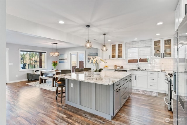 kitchen featuring gray cabinets, a kitchen island, decorative light fixtures, white cabinetry, and backsplash