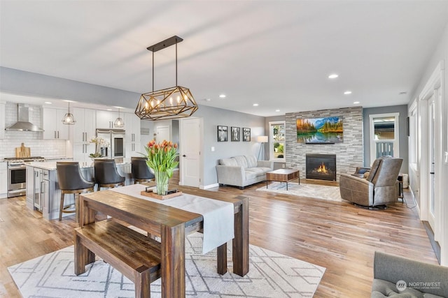 dining room with a stone fireplace and light hardwood / wood-style flooring