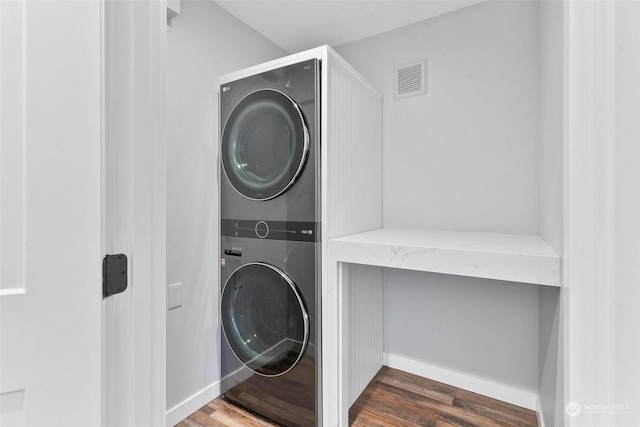 laundry room with stacked washer and dryer and dark hardwood / wood-style floors