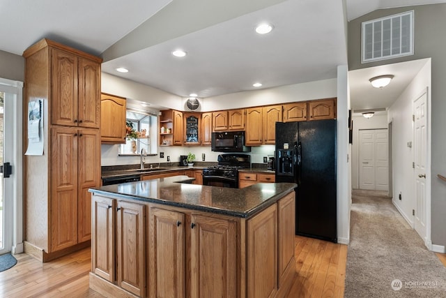 kitchen featuring lofted ceiling, a center island, sink, and black appliances