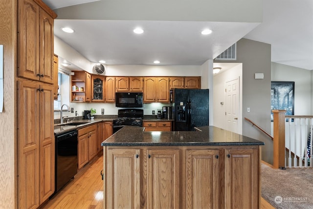 kitchen featuring lofted ceiling, sink, dark stone countertops, black appliances, and a kitchen island