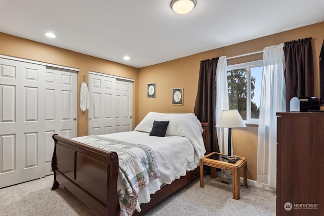 bedroom featuring multiple closets and light colored carpet