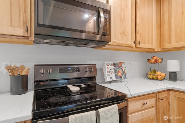 kitchen with appliances with stainless steel finishes, light brown cabinets, and light stone counters