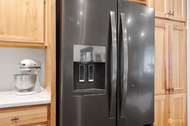 room details featuring light brown cabinets and stainless steel fridge