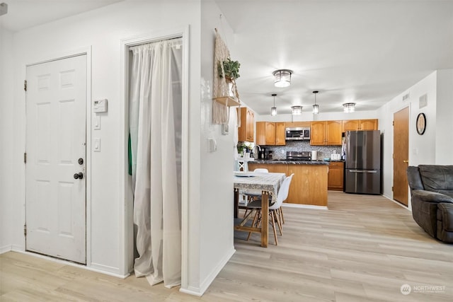 kitchen featuring a breakfast bar, decorative backsplash, stainless steel appliances, and light hardwood / wood-style flooring