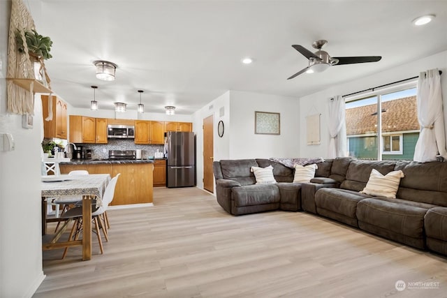 living room with ceiling fan, sink, and light hardwood / wood-style flooring