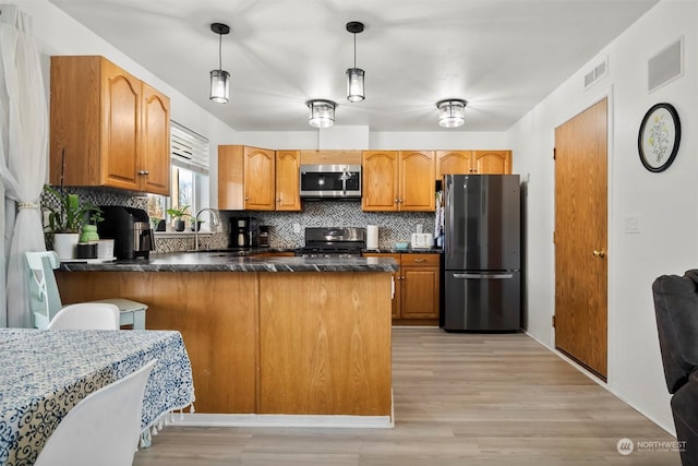 kitchen featuring decorative backsplash, hanging light fixtures, appliances with stainless steel finishes, and kitchen peninsula