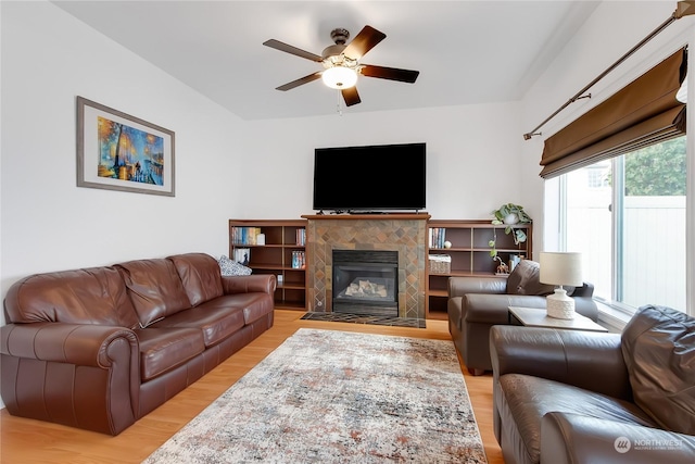 living room with ceiling fan, light hardwood / wood-style flooring, and a tiled fireplace