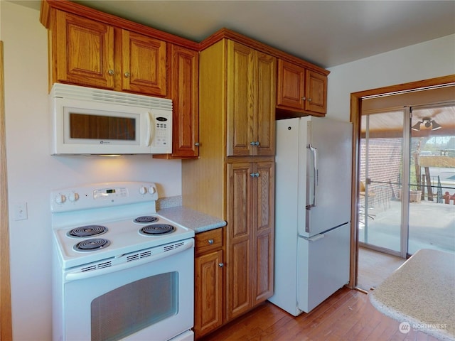 kitchen with white appliances and light hardwood / wood-style flooring