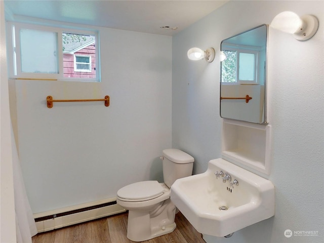 bathroom featuring toilet, baseboard heating, plenty of natural light, and sink