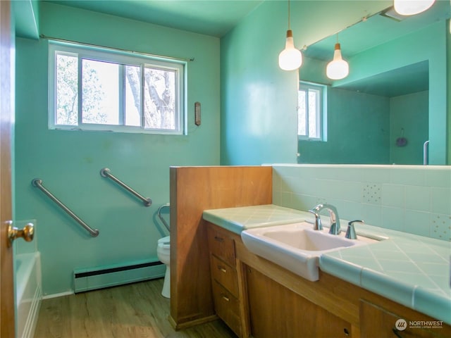 bathroom with a baseboard radiator, vanity, backsplash, toilet, and hardwood / wood-style flooring