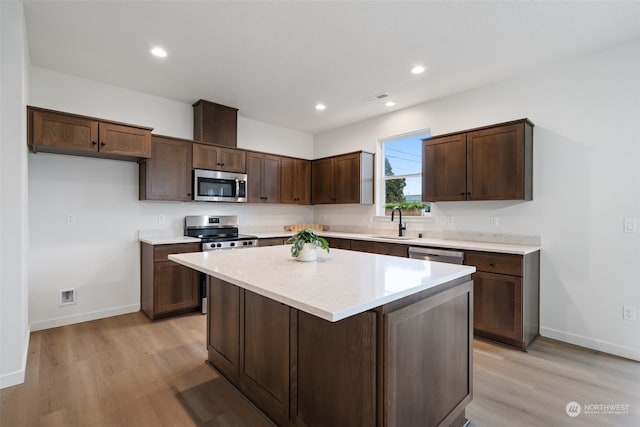 kitchen with a kitchen island, sink, dark brown cabinetry, light wood-type flooring, and appliances with stainless steel finishes