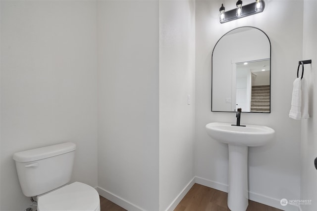 bathroom with toilet, hardwood / wood-style flooring, and sink