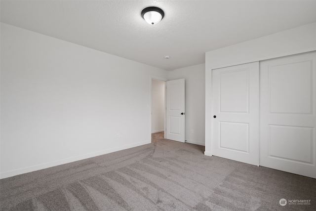 unfurnished bedroom with carpet, a closet, and a textured ceiling