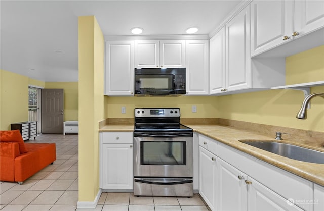 kitchen featuring light tile patterned floors, white cabinetry, sink, and stainless steel electric range