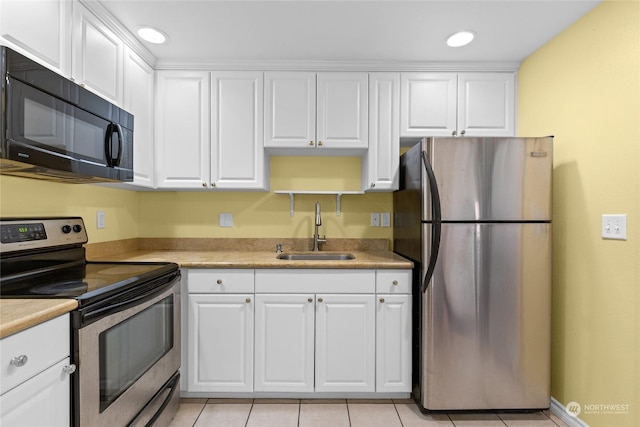 kitchen with sink, white cabinetry, appliances with stainless steel finishes, and light tile patterned flooring