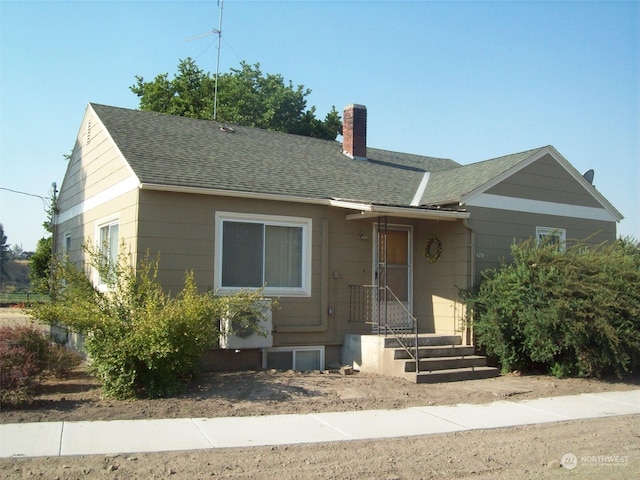 view of front of property with a shingled roof and a chimney