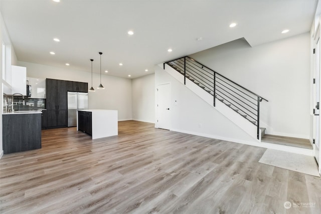 kitchen with decorative light fixtures, white cabinets, built in refrigerator, a kitchen island, and light hardwood / wood-style floors