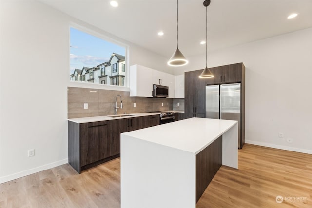 kitchen with hanging light fixtures, sink, white cabinets, a kitchen island, and stainless steel appliances