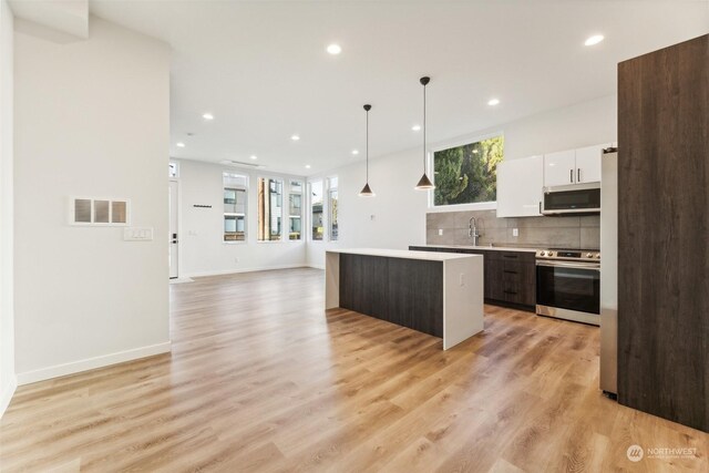 kitchen featuring appliances with stainless steel finishes, a center island, decorative light fixtures, white cabinetry, and dark brown cabinets