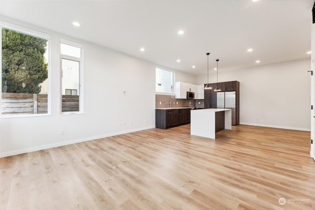 kitchen with pendant lighting, a kitchen island, white cabinetry, stainless steel appliances, and dark brown cabinets