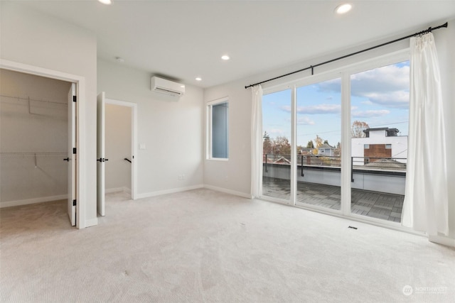 unfurnished bedroom with access to exterior, light colored carpet, a wall unit AC, and a walk in closet