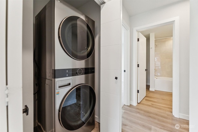 laundry room featuring stacked washer and clothes dryer and light hardwood / wood-style flooring